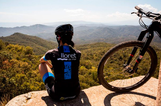 ciclista contempla a paisagem do alto de uma montanha