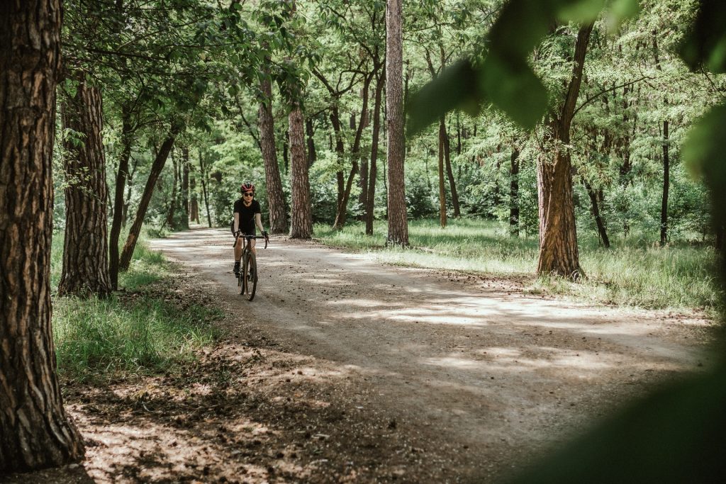 Mulher em gravel bike no meio de uma estrada entre as árvores