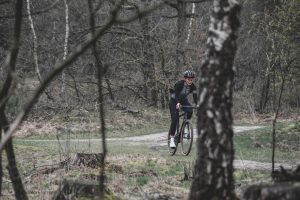 Mulher andando de gravel bike em meio à gloresta em dia nublado