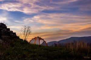 Camping com barraca branca e laranjo no alto da montanha em meio à natureza é sustentável