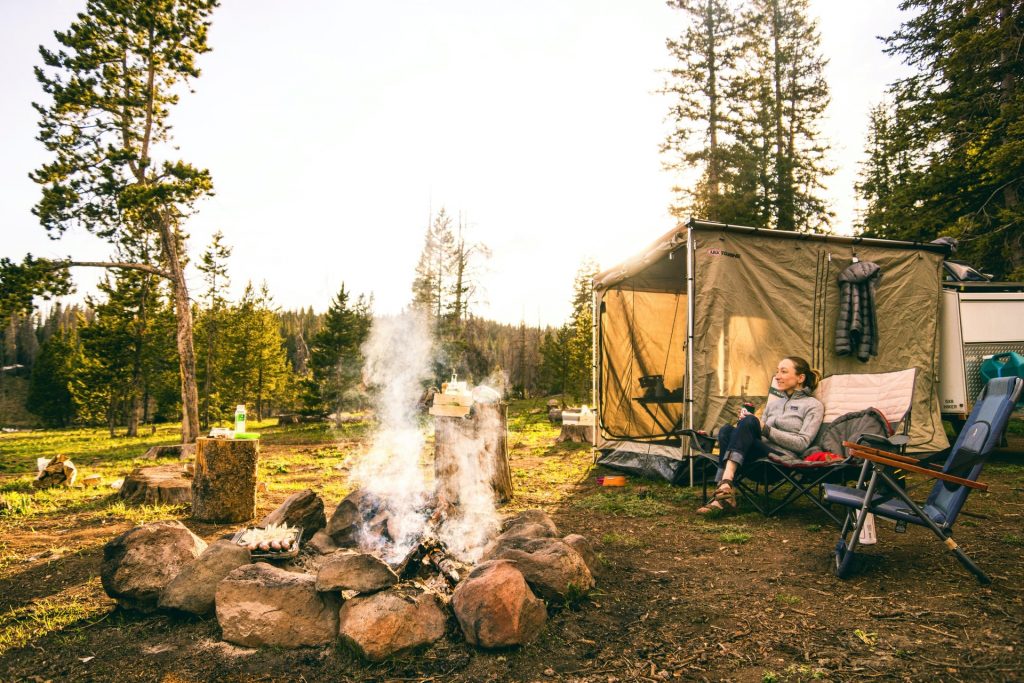 Mulher em camping com fogueira entre pedras