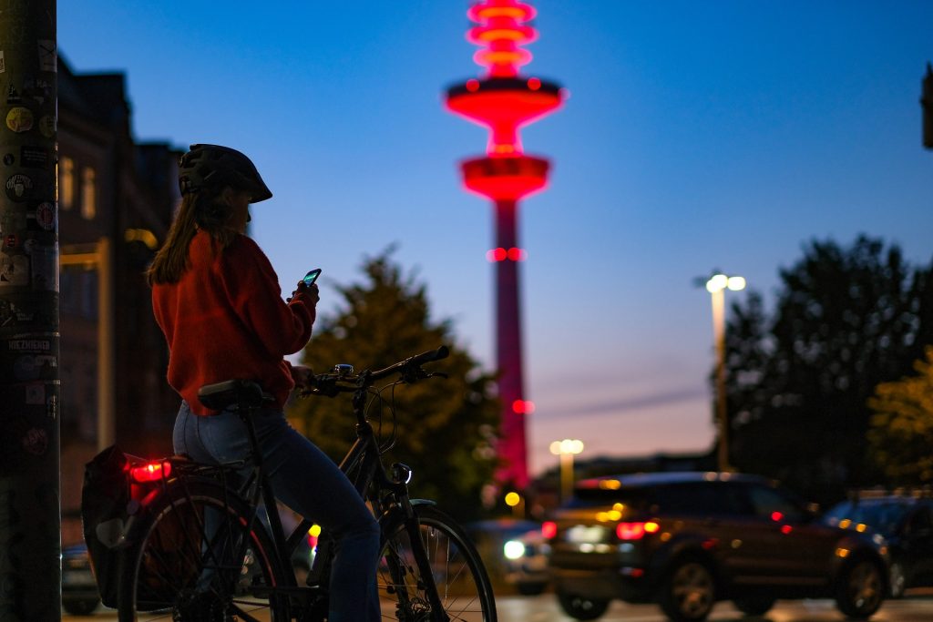 Mulher com capacete sai para pedalar à noite em bicicleta com farol traseiro