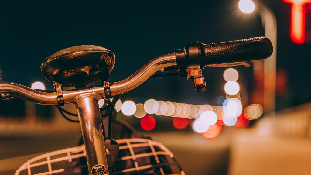 Guidão de bicicleta retrô com farol apagado em meio à cidade durante à noite